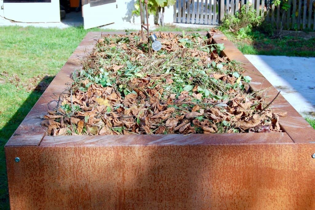 Garten winterfest: mit Laub bedecktes Hochbeet